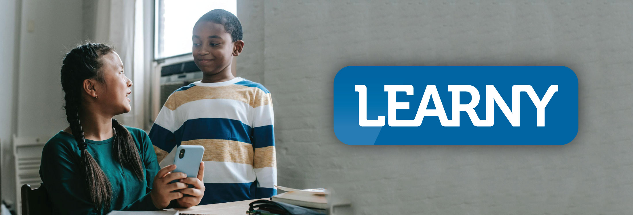home banner with two young scoolchildren looking at a cellphone.
